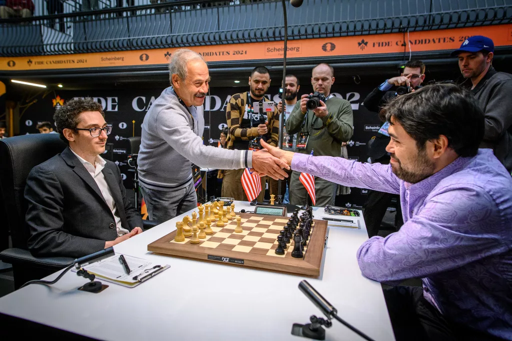 Nakamura saluda a Isai Scheinberg, patrocinador del Candidatos, en presencia de Fabiano Caruana. Foto: FIDE / Michal Walusza