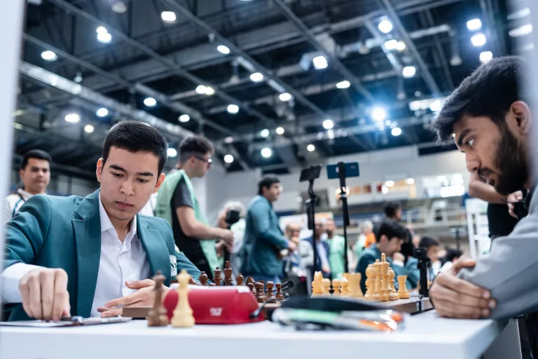 Nordibek Abdusattorov y Gukesh. Muy al fondo, se puede ver al capitán del equipo uzbeko, Vladimir Kramnik. Foto: Maria Emelianova