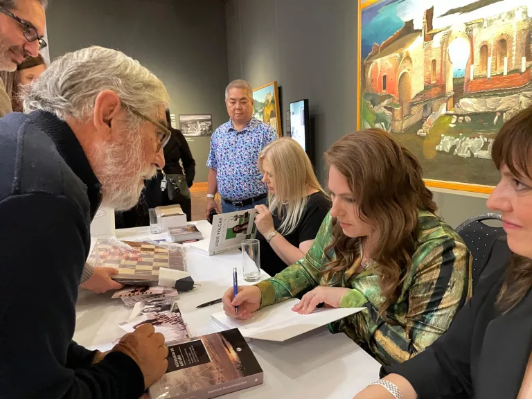 Juan Campos, con Judit Polgar, firmando su libro. A su lado están sus hermanas, Susan y Sofia, a la que podemos ver de refilón. Foto cedida por Juan Campos