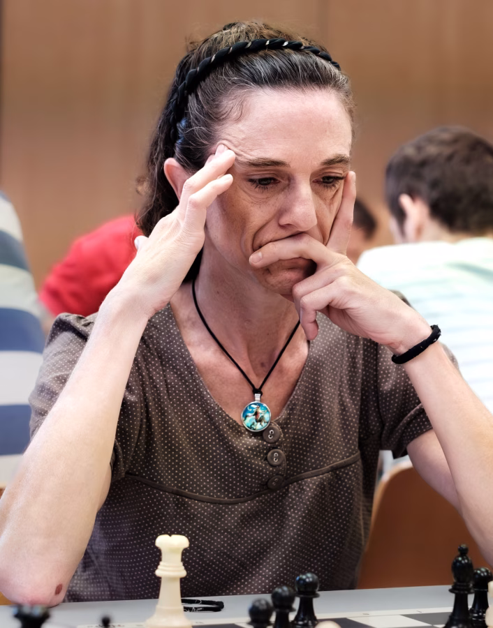 Mujer jugando ajedrez concentrada.
