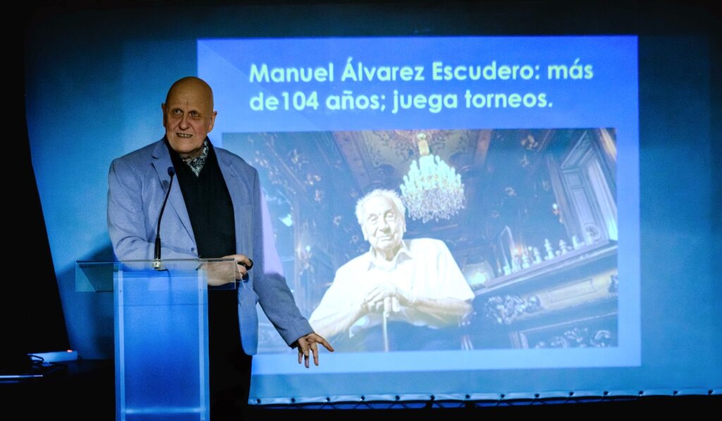 Leontxo García, en la presentación de GymChess en Madrid. De fondo, Manuel Álvarez, de 104 años, un ejemplo único de resistencia al deterioro cognitivo causado por el envejecimiento. Fotos: FMB / Damas y Reyes